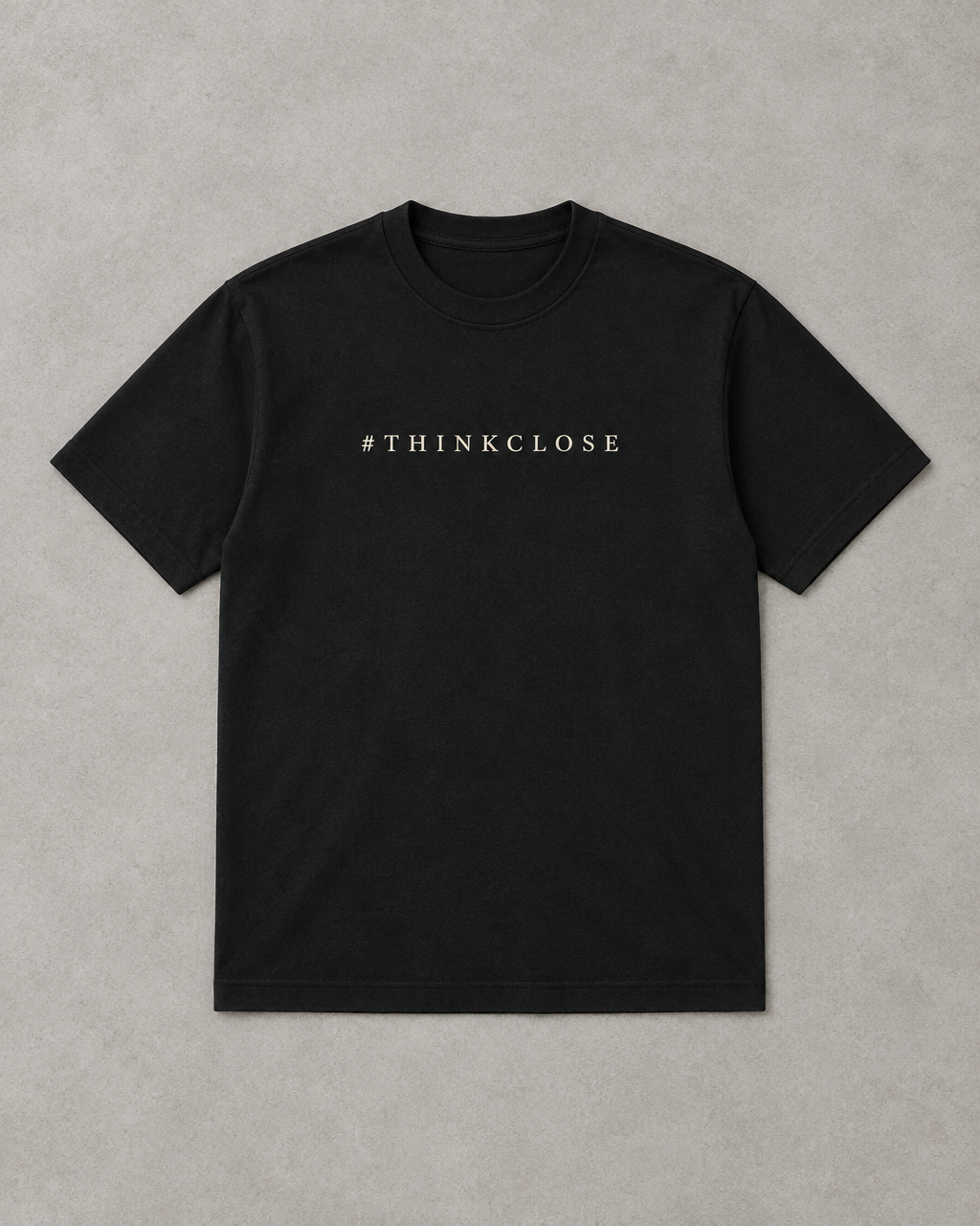 ThinkClose placeholder — black heavyweight tee printed with #thinkclose, laid flat on a light grey surface